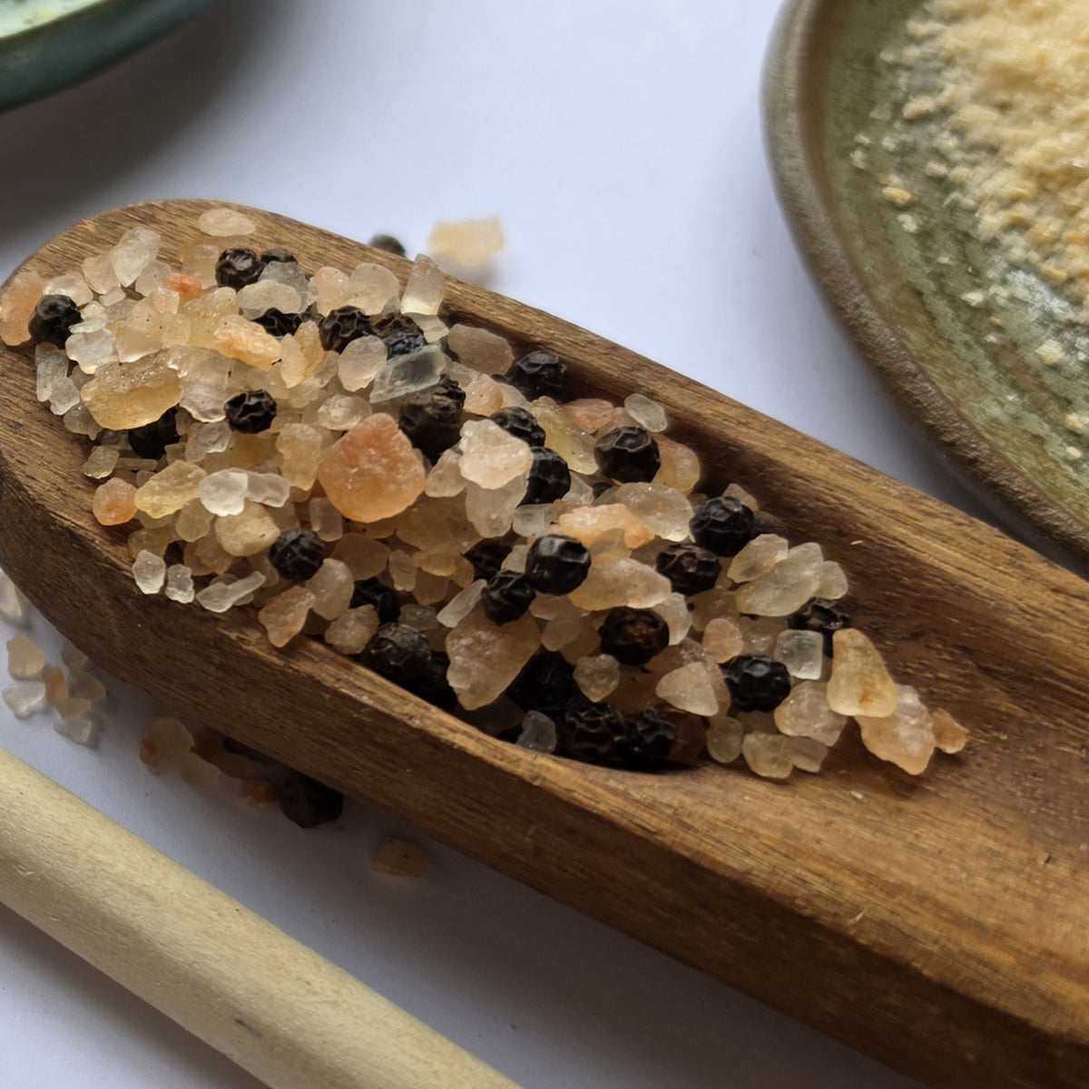 Rock salt and black peppercorns on a wooden scoop